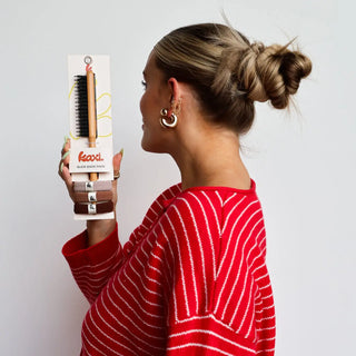 Woman holding a Kevla hair styling product against a plain background