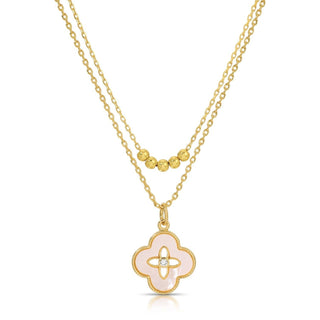 Gold necklace with a pink clover-shaped pendant on a white background