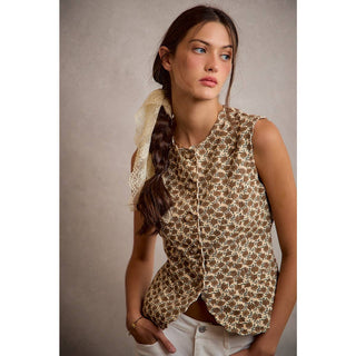 Woman wearing a sleeveless patterned top with a plain background