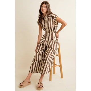 Woman wearing a striped dress standing on a stool against a plain background