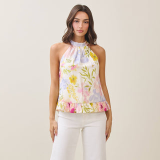 Woman wearing a floral halter top and white pants on a beige background