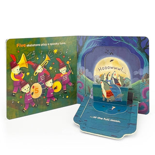 Pop-up children's book with skeletons playing music and a fish under a full moon.