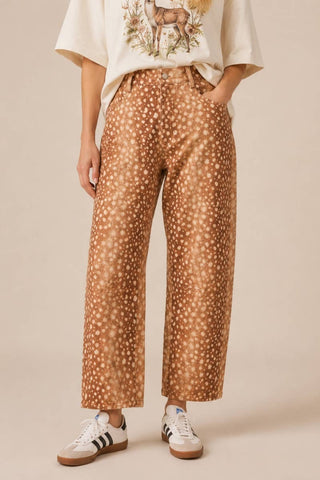Person wearing brown patterned pants with a beige background