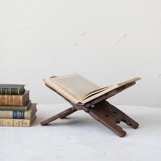Wooden book stand with an open book on a white surface