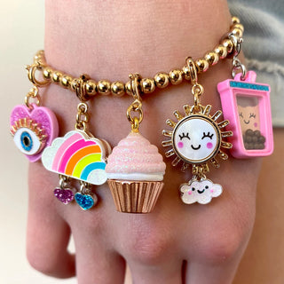 A close-up of a gold beaded charm bracelet worn on a wrist, featuring multiple colorful charms including a pink heart with an eye, a rainbow cloud, a pink cupcake, a smiling sun, a small cloud, and a pink drink can.