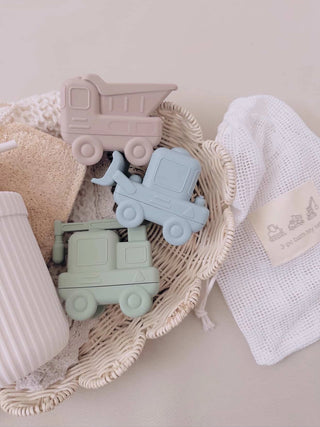 Set of silicone baby teether toys in pastel colors on a soft surface with a textured blanket.