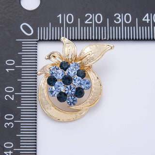 Gold brooch with blue gemstones next to a ruler for size reference