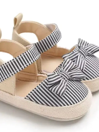 Children's sandals with striped straps and a bow on a white background