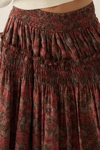 Close-up of a smocked tiered skirt with a dark red and brown floral pattern, paired with a white ribbed top.