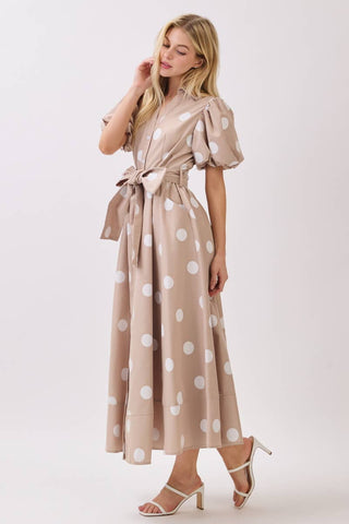 Woman wearing a beige dress with white polka dots on a white background
