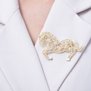 Gold horse-shaped brooch on a white blazer
