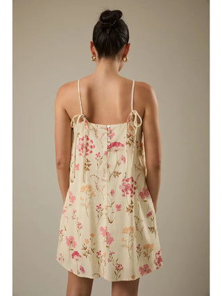 Woman wearing a floral dress with thin straps against a neutral background