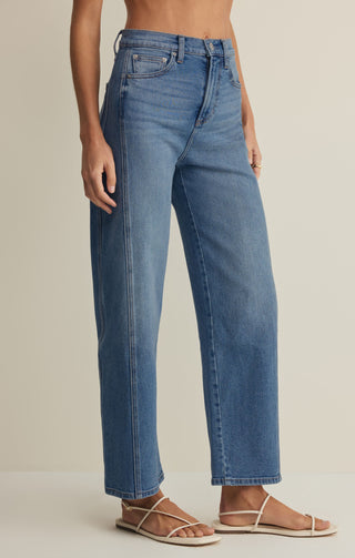 Person wearing blue jeans on a plain background