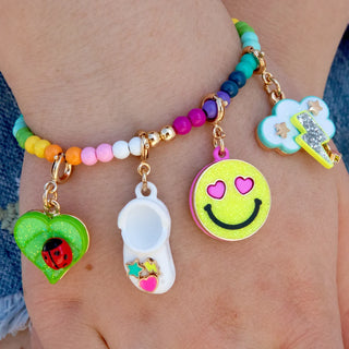 Colorful beaded bracelet with various charms on a wrist.