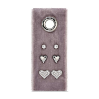 Set of silver heart-shaped earrings on a purple velvet card with a round metal clasp.
