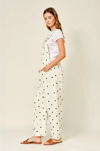 Woman wearing a white t-shirt and polka dot pants on a plain background