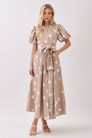 Woman wearing a beige dress with white polka dots on a white background