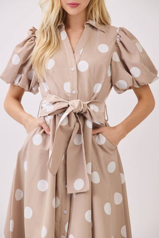 Beige dress with white polka dots worn by a person on a plain background