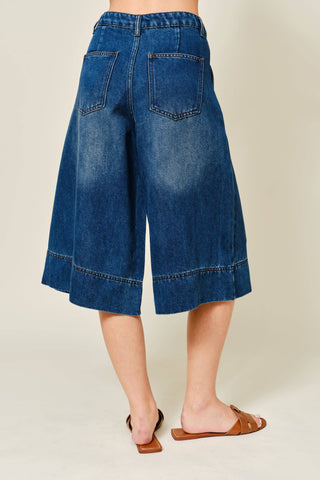 Blue denim culottes worn by a person on a beige background