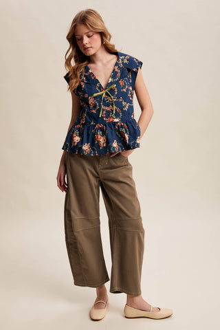 Woman wearing a floral top and brown pants on a beige background