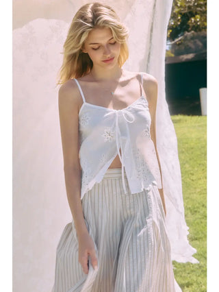 Woman wearing a white lace top and light-colored skirt outdoors