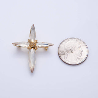Gold and clear crystal brooch next to a quarter for scale on a white background