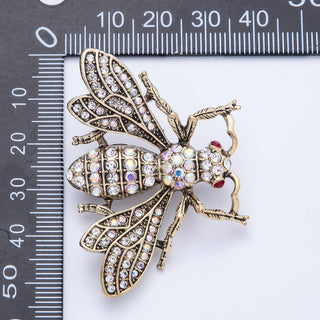 Decorative bee brooch with rhinestones on a white background with a ruler for scale.