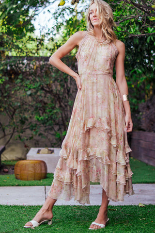 Woman in a floral dress standing outdoors with greenery in the background