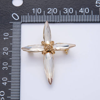 Gold and clear brooch on a white background with a ruler for scale.