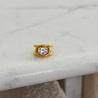 Gold earring with a diamond on a marble surface