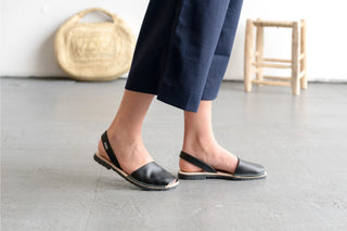 Person wearing black sandals on a light gray floor with a woven basket in the background.