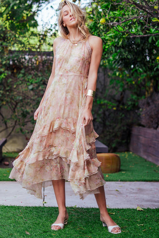 Woman wearing a floral dress standing outdoors with greenery in the background