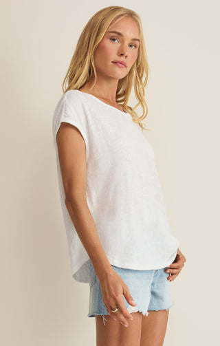 Woman wearing a white top and light blue shorts against a beige background