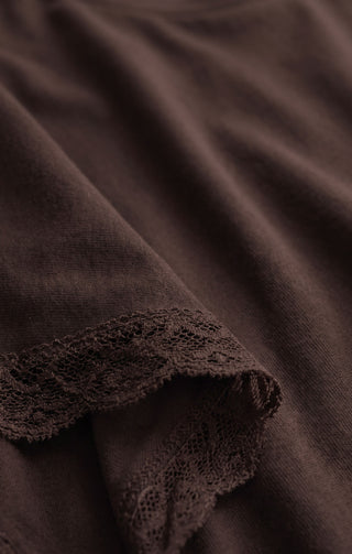 Close-up of dark brown fabric with a scalloped lace trim along the edge.