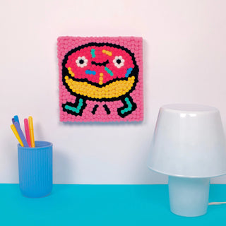 Colorful donut-themed wall art on a white wall with a blue surface and lamp.