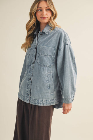 Woman wearing a light blue denim shirt on a beige background