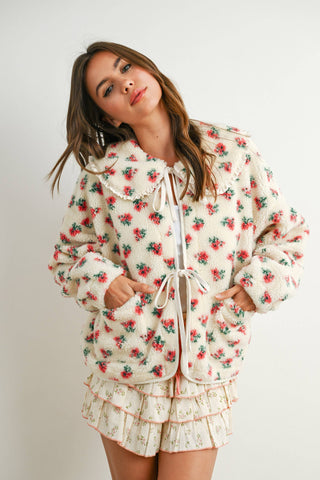 Woman wearing a floral patterned outfit on a plain background