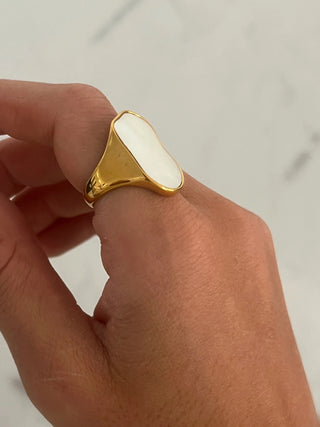 Gold ring with a white stone on a neutral background