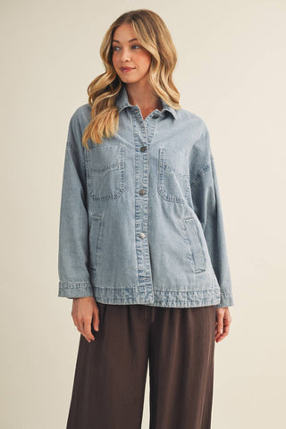 Woman wearing a light blue denim jacket on a beige background