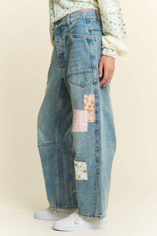 Patchwork jeans worn by a person on a beige background