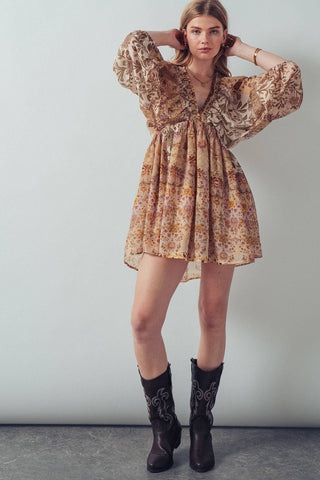 Woman wearing a floral dress and cowboy boots against a plain background