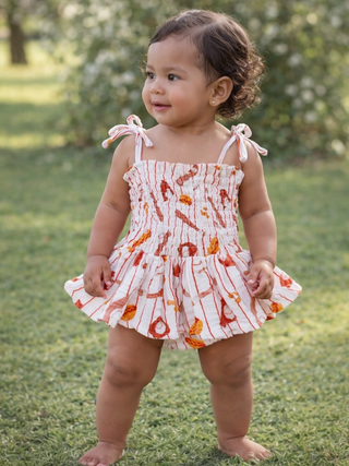 Child wearing a floral dress standing on grass with blurred background