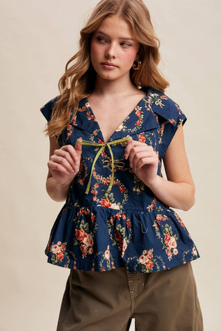 Woman wearing a floral peplum top against a beige background