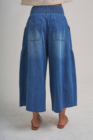 Blue denim wide-leg pants worn by a person on a white background