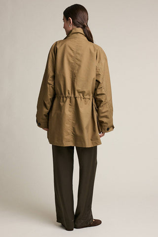 Person wearing a beige trench coat on a plain background