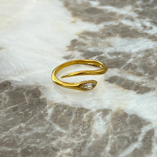 Gold ring with a diamond on a marble surface