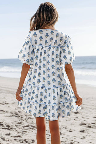 Woman in a floral dress standing on a beach with ocean view