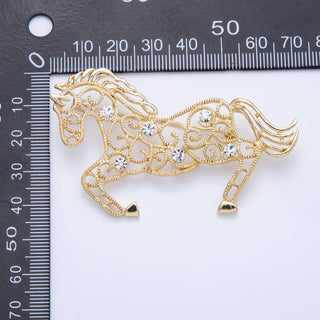 Gold horse-shaped brooch with rhinestones on a white background with a ruler for scale.