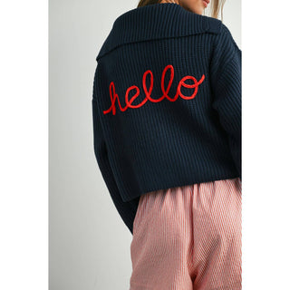 Navy blue jacket with red 'hello' text on the back, worn by a person with pink pants.