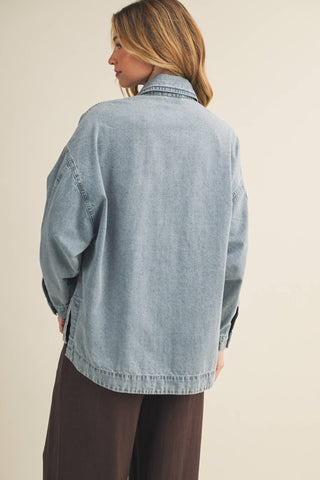 Woman wearing a light blue denim jacket on a beige background
